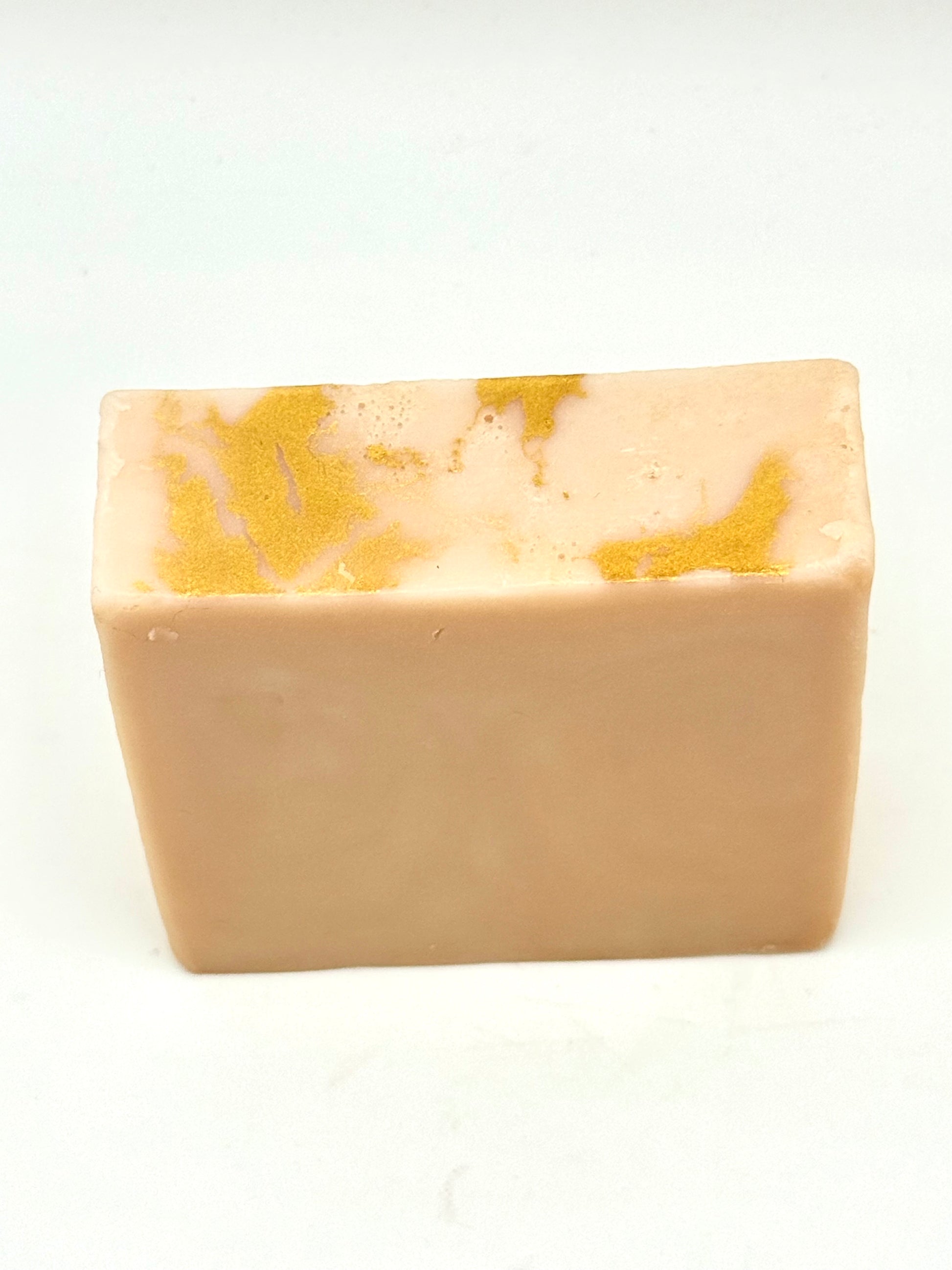 Rectangular bar of soap with gold marbling on top on a white background