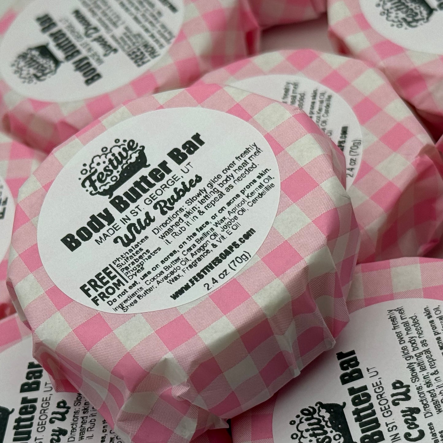 Body butter bars with pink checkered wrappers and visible labels.