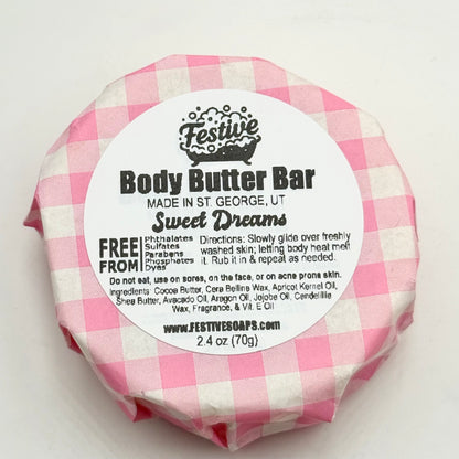Body butter bar with pink and white checkered wrapper on a white background