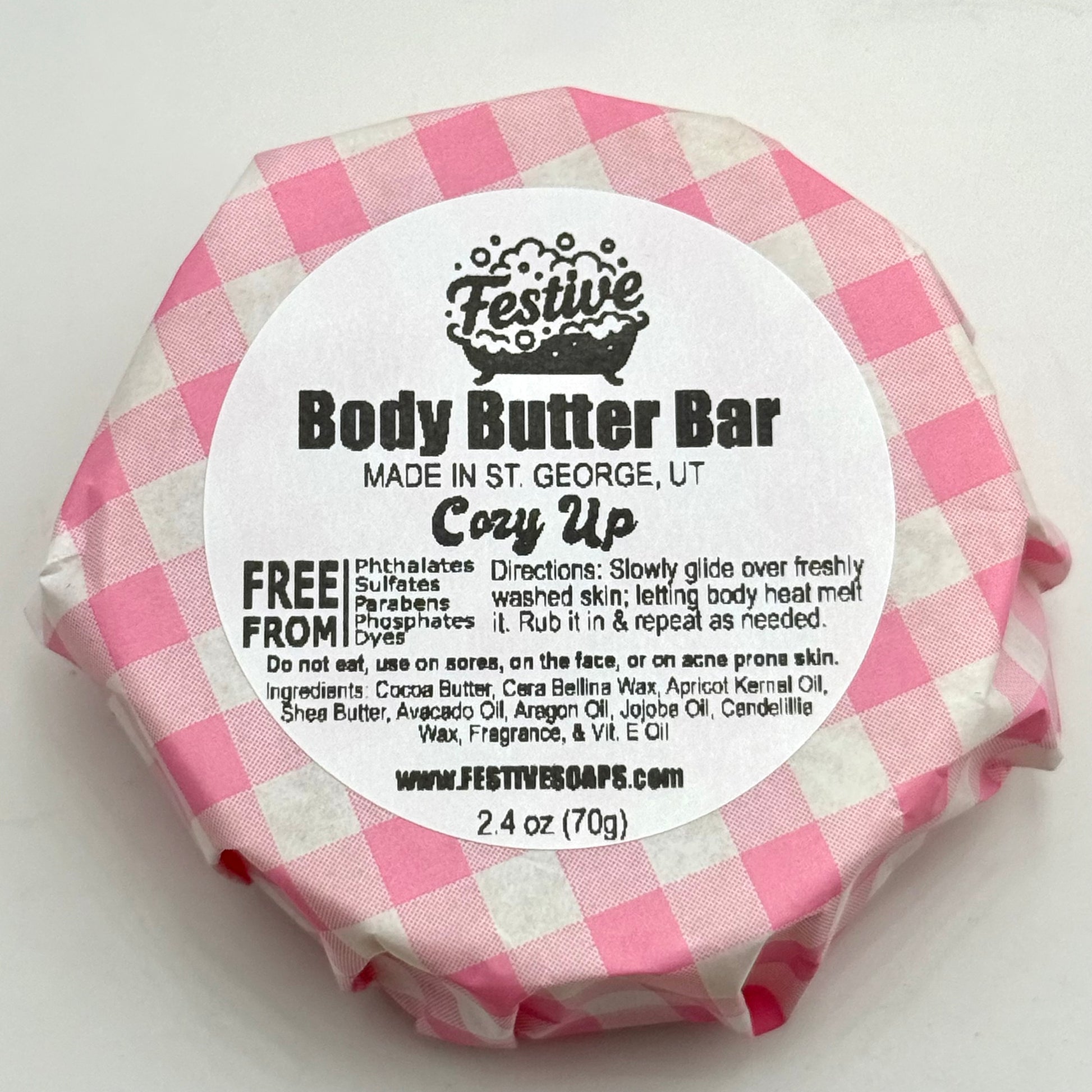 Body butter bar wrapped in pink and white checkered paper with a label on a white background