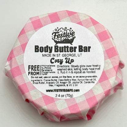 Body butter bar wrapped in pink and white checkered paper with a label on a white background